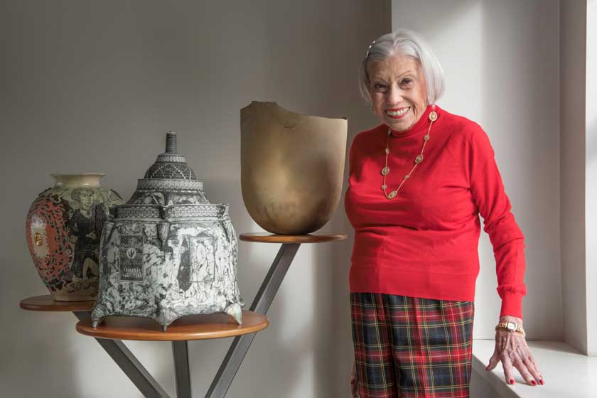 Nanette Laitman standing with 3 pieces of ceramic art